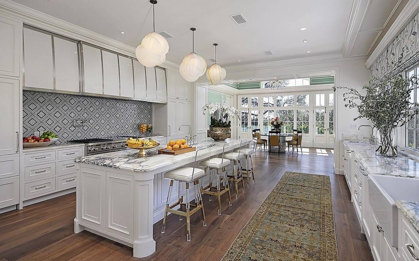 La cocina es muy amplia y posee el mobiliario en blanco de estilo clásico. No falta una gran isla central de mármol para que toda la familia pueda compartir el espacio. Comunica además con el comedor que a su vez tiene una gran cristalera y las paredes en tono verdoso que le aportan un acabado muy alegre.