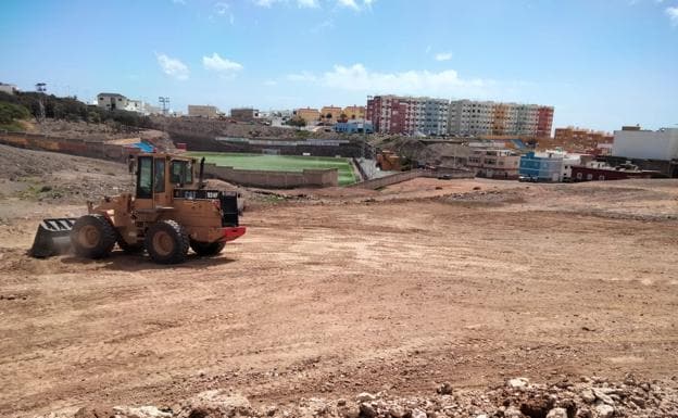 Un tractor interviene para allanar un terreno que se usará para aparcar. 