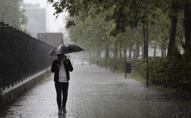 Un hombre se protege de la lluvia con un paraguas.