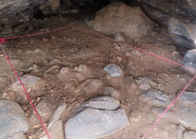 Imagen secundaria 1 - Acceso de la cueva, zona delimitada en el interior y uno de los trabajadores en lo alto del talud. 