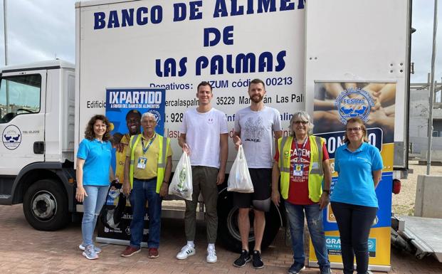 Los jugadores del Granca Salvó y Shurna posan con posan con voluntarios de CaixaBank y del Banco de Alimentos. 