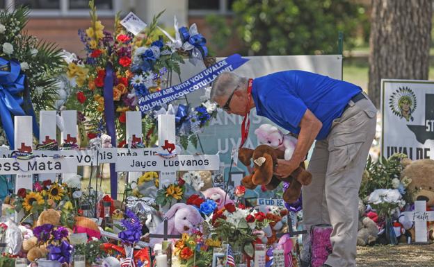 Un voluntario ayuda a colocar las decenas de flores, animales de peluche y otros objetos depositados en el memorial ciudadano por las victimas de la masacre de Uvalde (Texas).