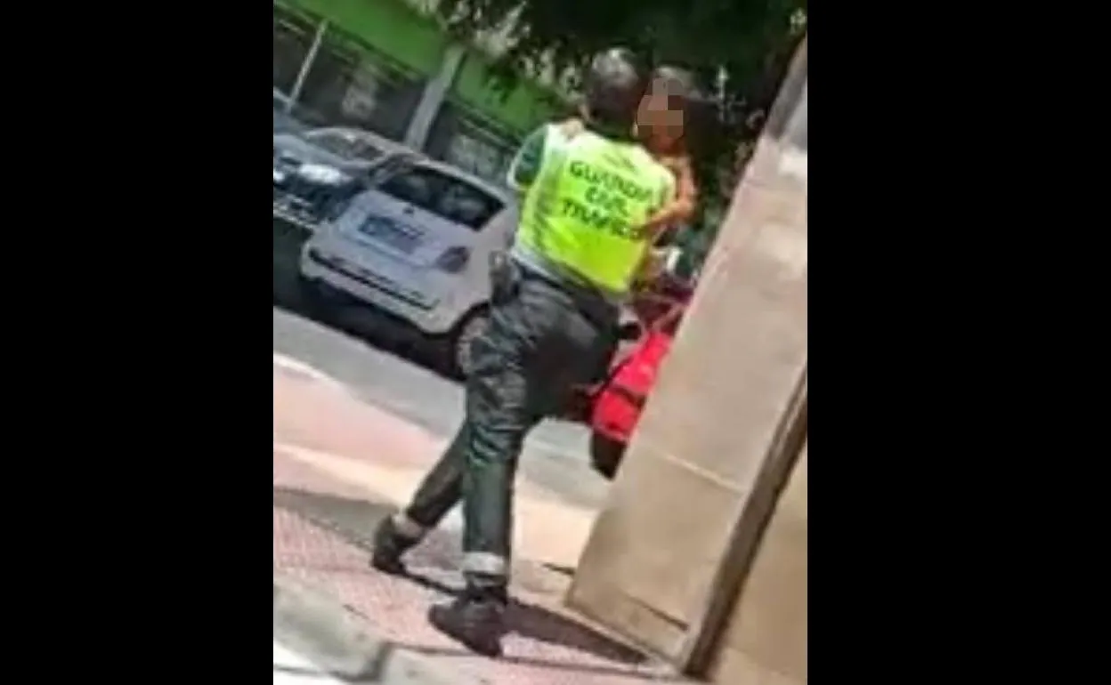 Un agente lleva en brazos a la menor hallada sola. 