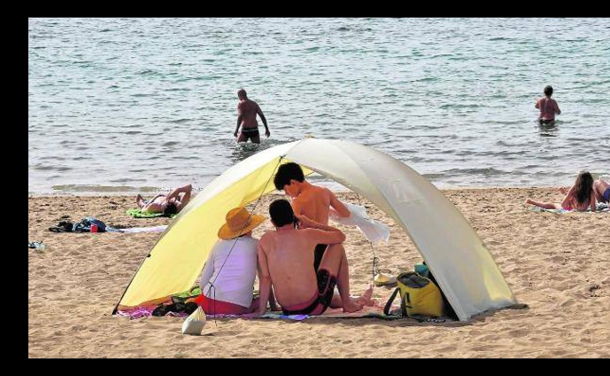 Una familia refugiándose del sol en la playa de Las Canteras