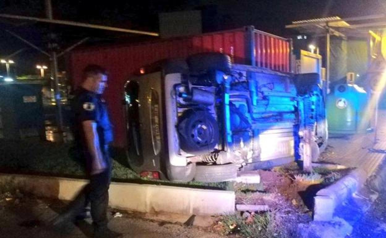 Un agente examina el coche que volcón en Miguel de Cervantes. 