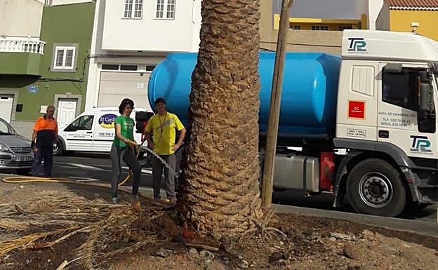 En la imagen, los vecinos y la cuba alquilada para el riego.