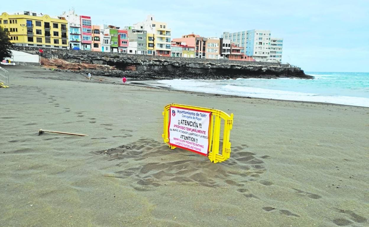 Cartel y valla con los que el Ayuntamiento informó ayer del cierre al baño de la playa de La Garita. 