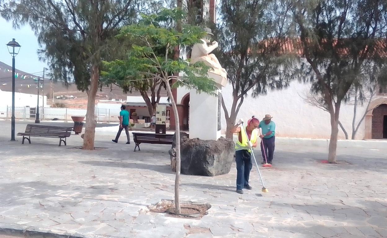 Trabajadores municipales limpian la plaza de la iglesia de Tetir por la cercanía de las fiestas. 