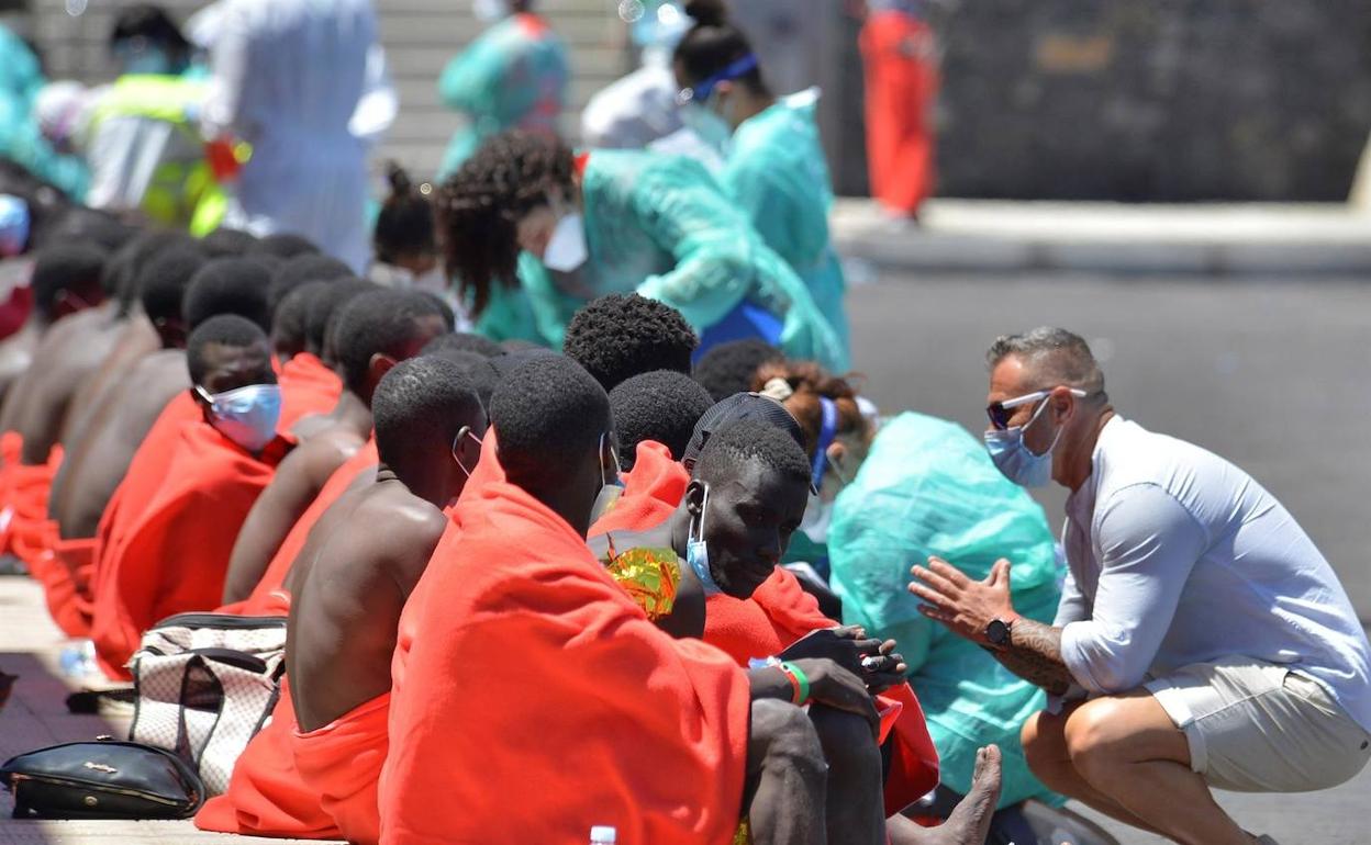 Los sanitarios atienden a un grupo de personas de una patera a su llegada a puerto. 