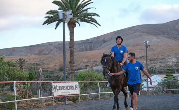 Raúl Toral, propietario de las cuadras Victoria, ayuda a Jorge David a llevar al caballo al trote. 