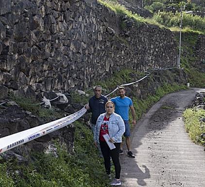Vecinos junto al muro que cayó y del que aún hay restos en la vía. 