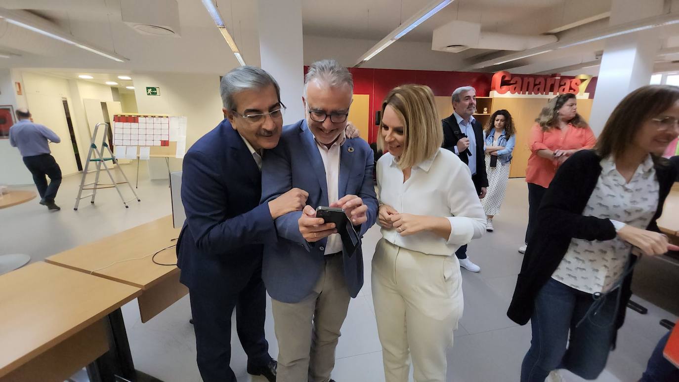 Los tres socios de gobierno observan una foto antigua en el móvil.