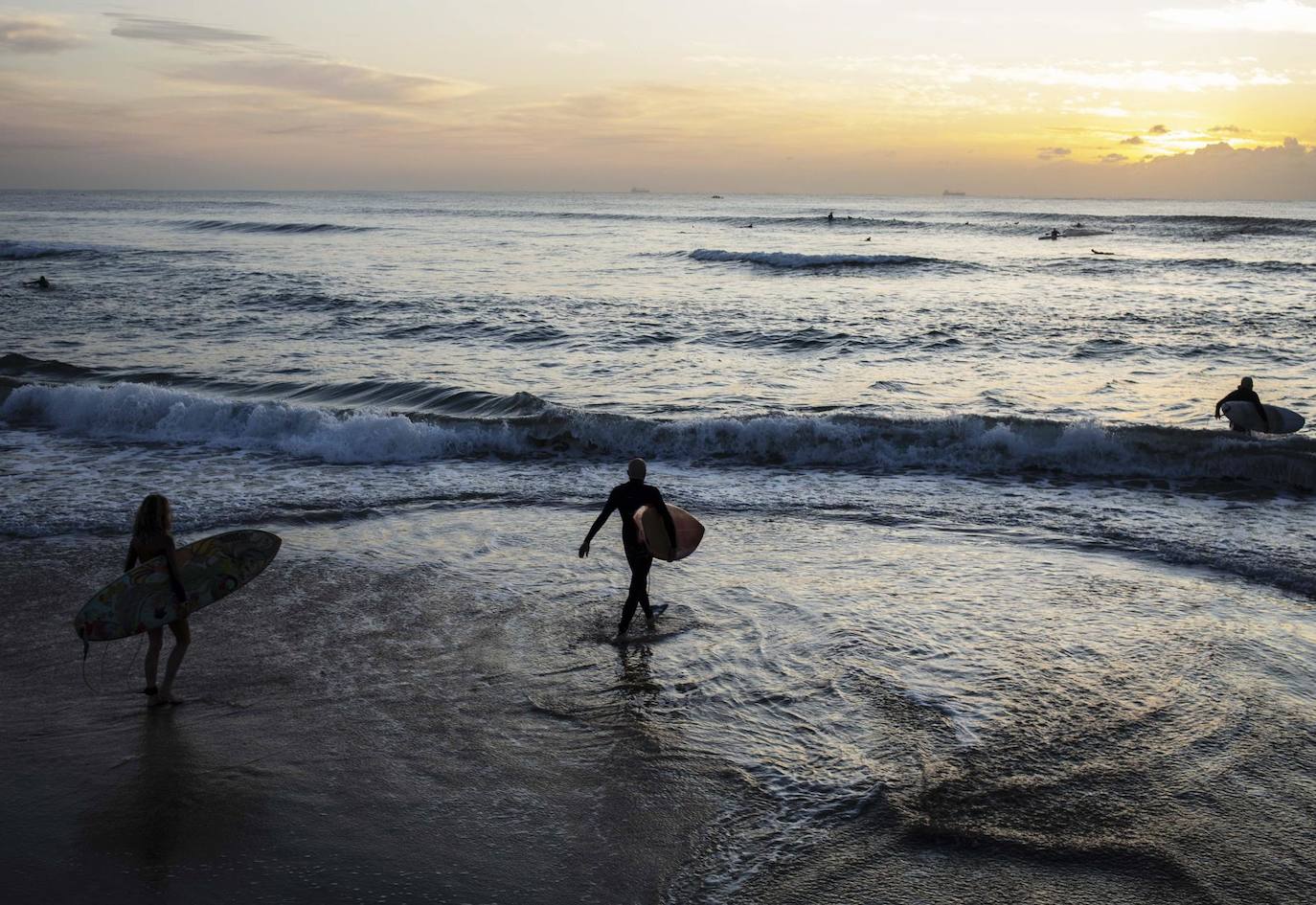 Surfistas se adentran en el mar en Durban, Sudáfrica, al amanecer.