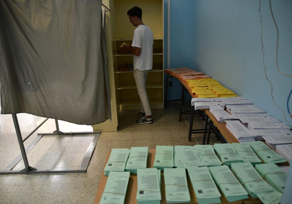 Un ciudadano escoge las papeletas para votar.