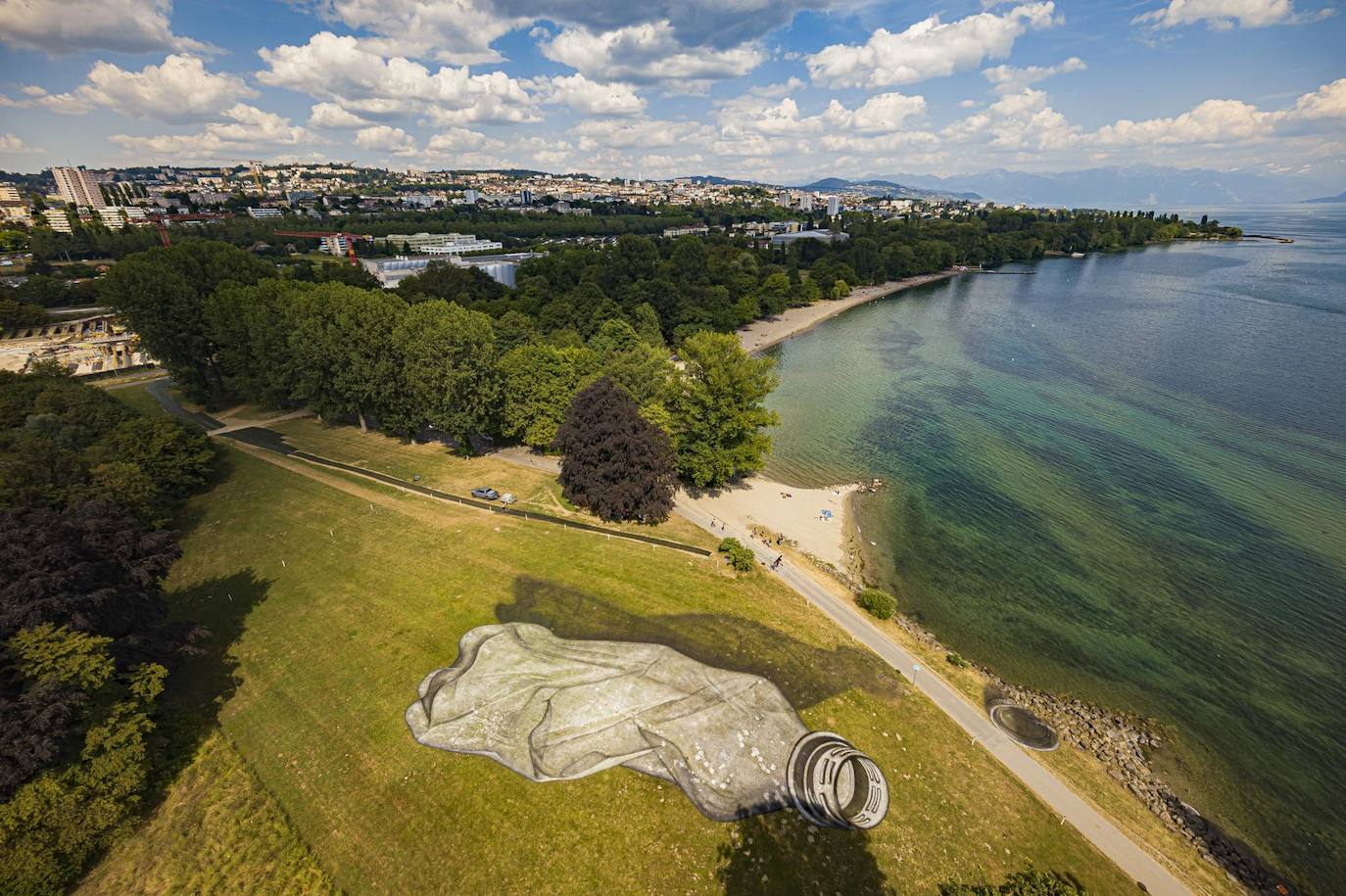 Una foto tomada por un dron muestra el cuadro de Land Art del artista Guillaume Lagros que representa una botella de plástico desechada cerca del lago Lemán en Lausana.