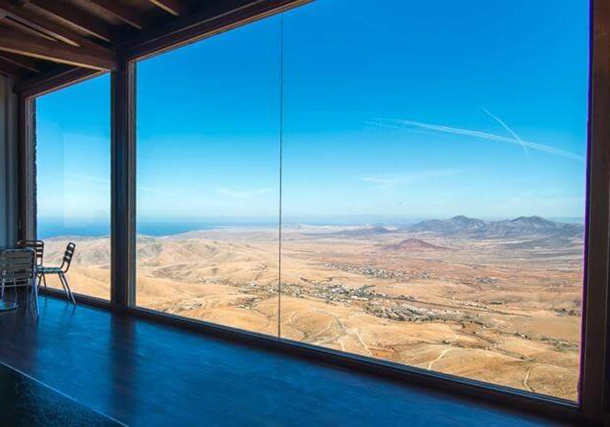 Serenas vistas del interior de Fuerteventura.- Este mirador es parada obligada para quien desee descubrir una Fuerteventura distinta a la de las postales turísticas. El interior de esta isla Reserva de la Biosfera de la Unesco sorprenderá al visitante por sus paisajes agrestes sin núcleos turísticos ni dunas. Ante el viajero se abre una sucesión casi infinita de colinas redondeadas y coloreadas de múltiples tonos ocre, y entre ellas, barrancos sinuosos con escasos pueblos y caseríos en sus fondos. Es sin duda un paisaje sorprendente que transmite serenidad y amplitud.