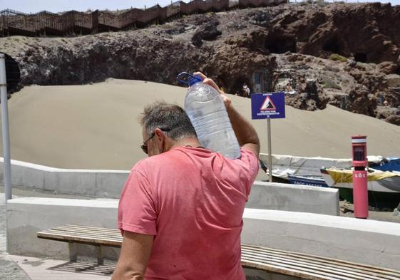 En la imagen, un hombre carga con una garrafa de agua para ayudar a los lagartos de El Burrero a superar la ola de calor.