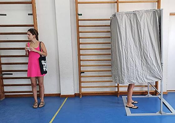 Una mujer espera para entrar en la cabina electoral durante el 23J.