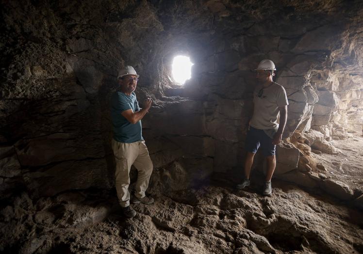 Imagen principal - En la foto superior, Abel Galindo y Bentejuí Motas, junto al orificio que pudo servir de entrada a la cueva. Debajo, diversos restos hallados durante la excavación.