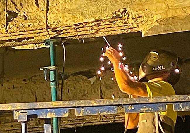 Detalle de un operario en plena tarea de reparación de las vigas bajo el puente.