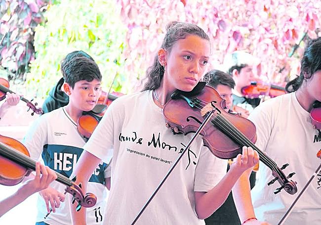 Integrantes de Barrios Orquestados tocan el violín.