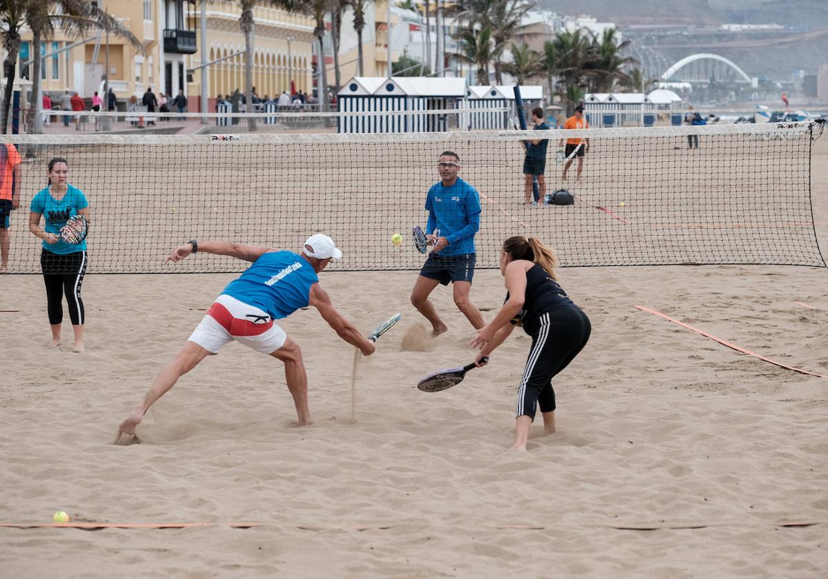 Cuatro jóvenes juegan al tenis playa en Las Canteras.