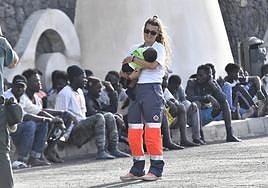 Una voluntaria de Cruz Roja atiende a un menor llegado, a bordo de un cayuco, al puerto de La Restinga, en El Hierro.