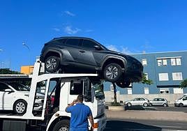 Imagen del vehículo a punto de caer de la grúa.