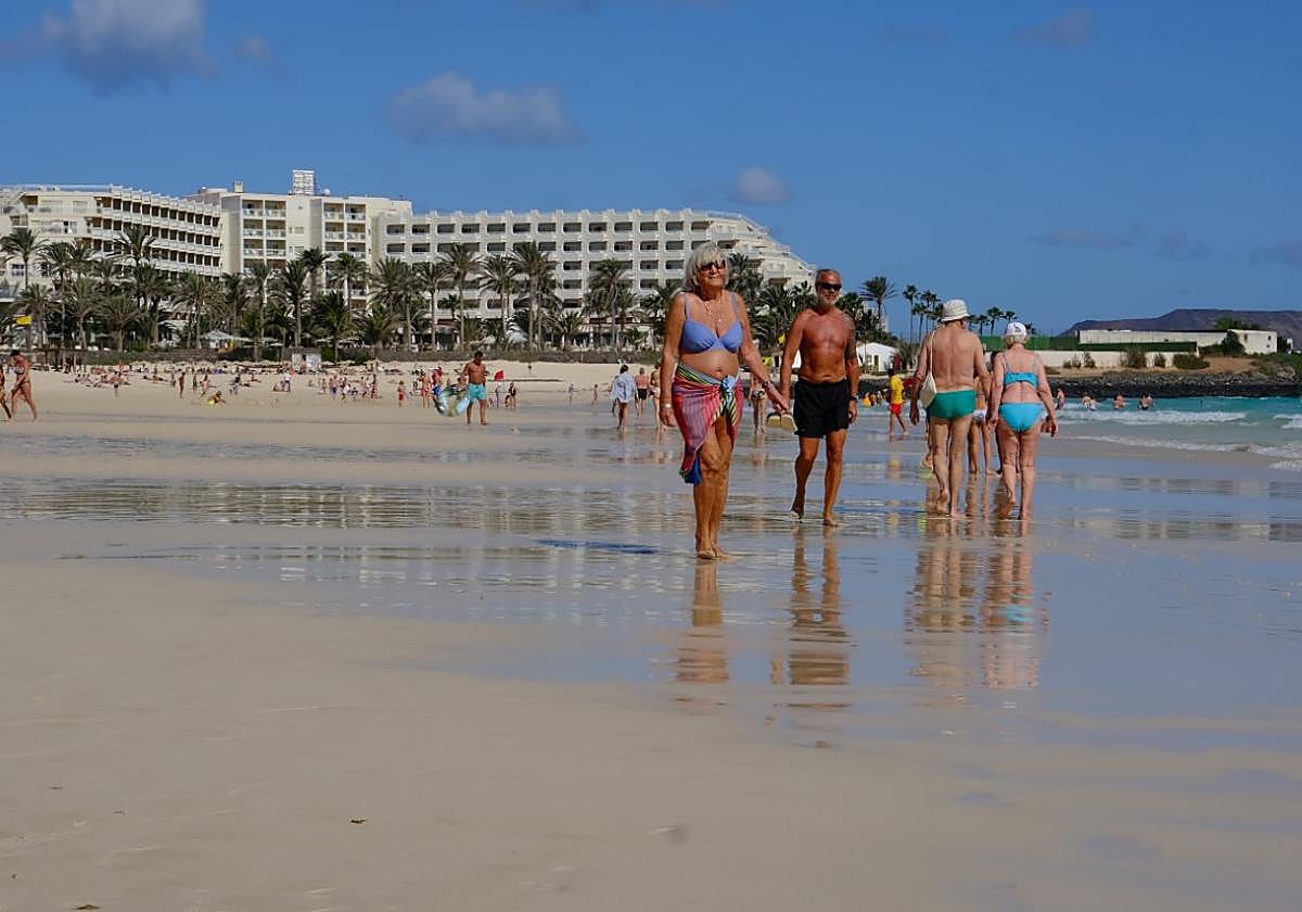 Turistas pasean por la orilla de las Grandes Playas de Corralejo, en el municipio de La Oliva.