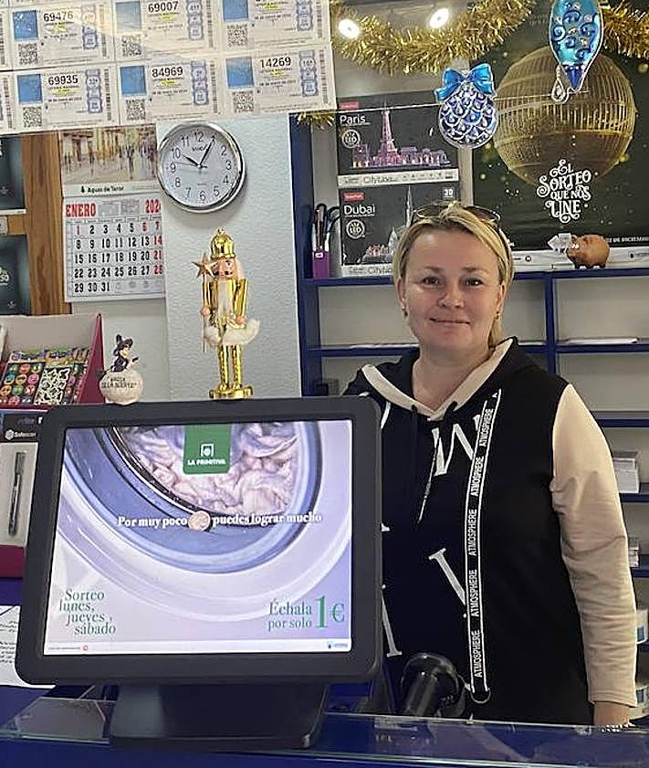 Imagen secundaria 2 - En la foto superior, Maximino Ojeda y otros dos trabajadores del receptor de la Estación de Servicio Pozo Izquierdo muestran su alegría por los 5 décimos vendidos de un quinto premio. En las dos imágenes de abajo, Guillermo Montoya, que dio un segundo premio, a través de la mampara desde la que atiende a sus clientes; y Ludmila Sablina en el receptor del Bazar La Plaza, en Playa de Arinaga (Agüimes). 
