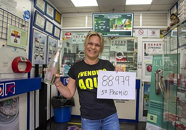 Alicia muestra orgullosa el cartel de uno de los dos quintos que se vendieron en la Tabaquería Monroy.