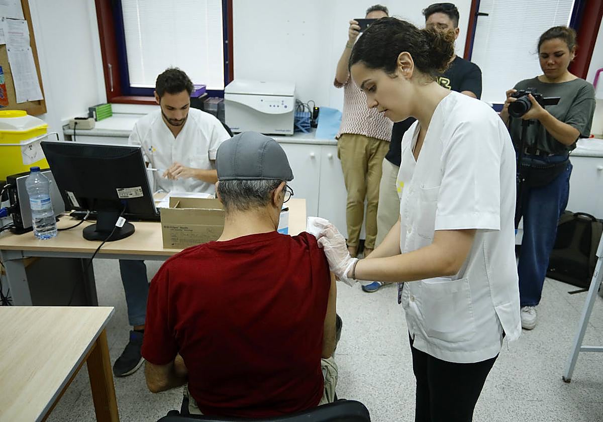 Una sanitaria pinchando a un hombre en el inicio de la campaña vacunal contra la gripe.