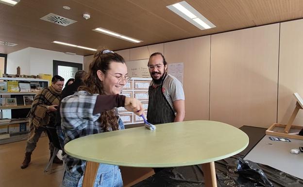 Una alumna, rodillo en mano, pintando una mesa. 