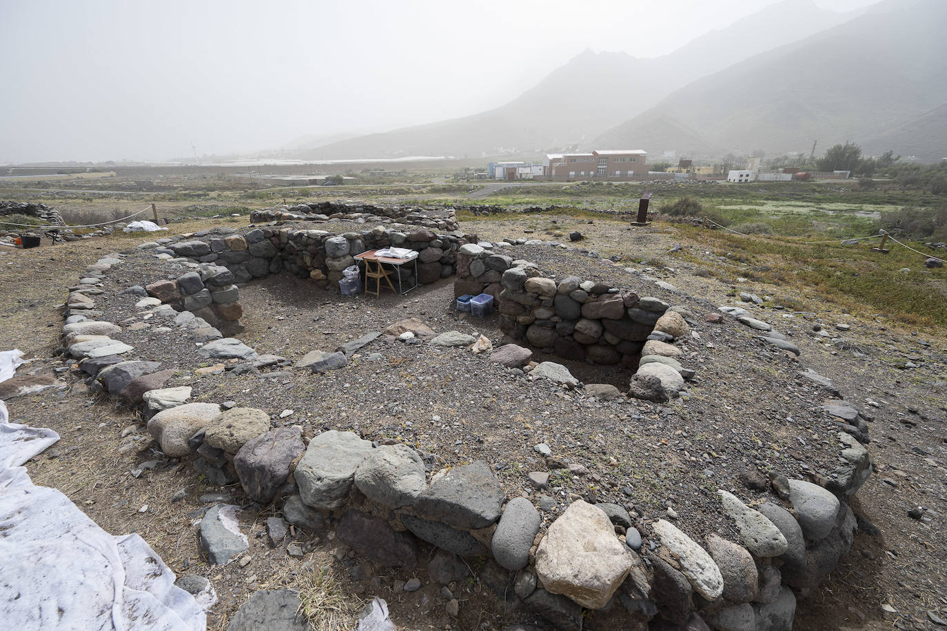 Imagen principal - Arriba, estructura cruciforme que también ha formado parte de esta campaña. Debajo, uno de los arqueólogos en faena y un ídolo hallado en el yacimiento. 