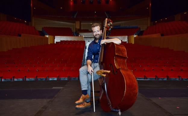 Juan Márquez posa con su contrabajo, en el escenario del Auditorio Alfredo Kraus, con el que ya se prepara para su reincorporación a la Orquesta Filarmónica de Gran Canaria.