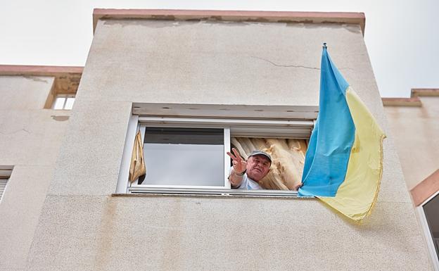 Oleg Lisovskyy, despliega la bandera ucraniana y hace el símbolo de la victoria en su casa de Puerto del Rosario. 