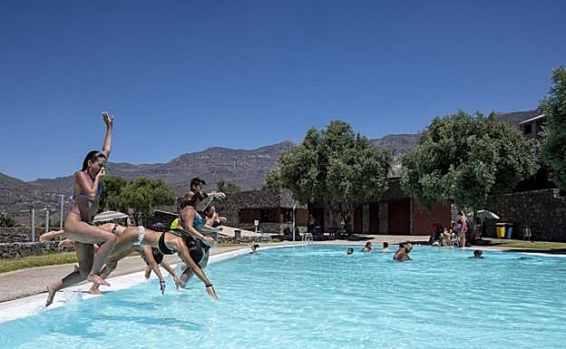 Un grupo se divierte saltando al agua en la piscina de Santa Lucía. 