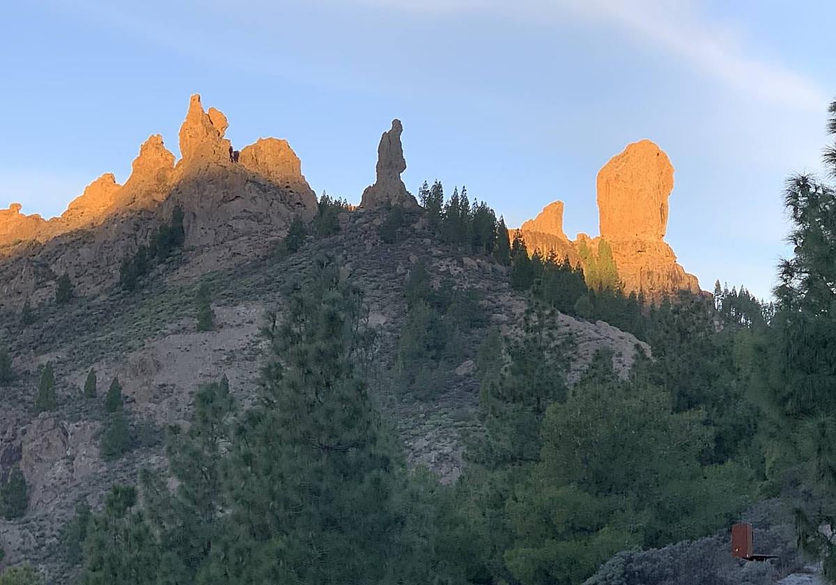 El Fraile, a la sombra, como recogido, mientras La Rana y el Roque Nublo brillan como el oro gracias al sol.