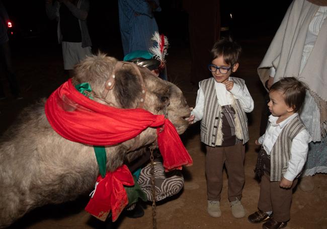 Dos niños, con uno de los camellos de los Reyes.
