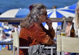 Una mujer fumando en una terraza de la playa de Las Canteras.