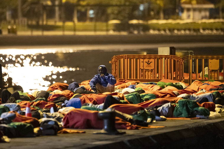 Un grupo de migrantes duerme al raso en el muelle de Los Cristianos.