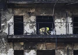Bomberos y Policía Científica inspeccionan un cuerpo en un balcón del edificio incendiado en el barrio de Campanar de València.