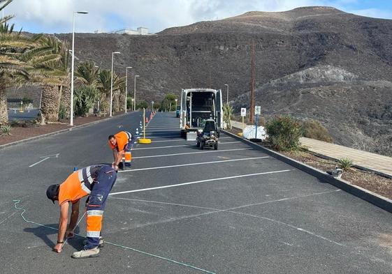 Trabajadores pintan las rayas de los aparcamientos.