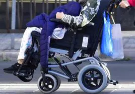 Imagen de archivo de una persona dependiente en silla de ruedas junto a su cuidadora.