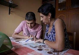 Kirian Herrera con su madre, Encarna García, en la cocina de su casa. Ella es la que se encarga de que el joven siga haciendo tareas escolares.