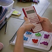 Imagen de archivo de una escolar con una calculadora en clase.