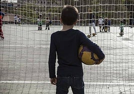 Imagen de un niño en el patio de su colegio viendo como otros juegan.