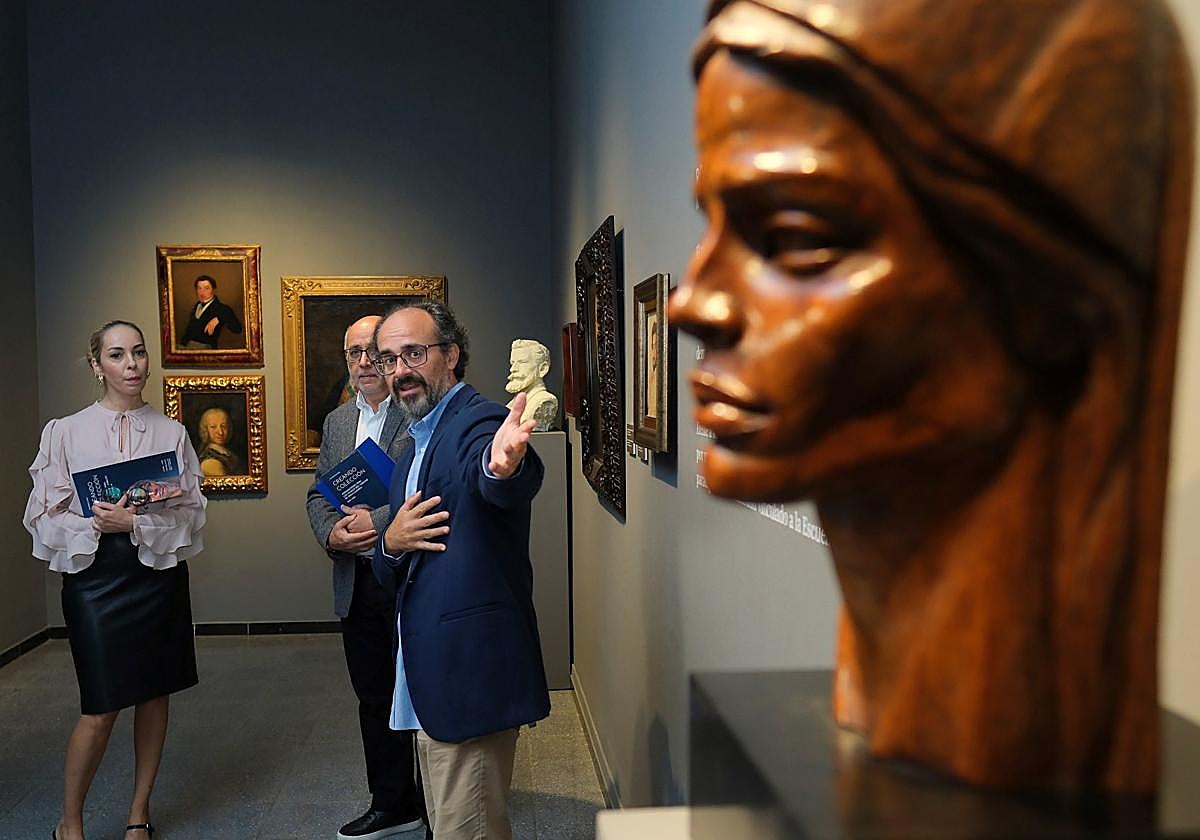 Guacimara Medina y Antonio Morales atienden a Javier Pueyo, que les ofrece detalles de una obra de la muestra.