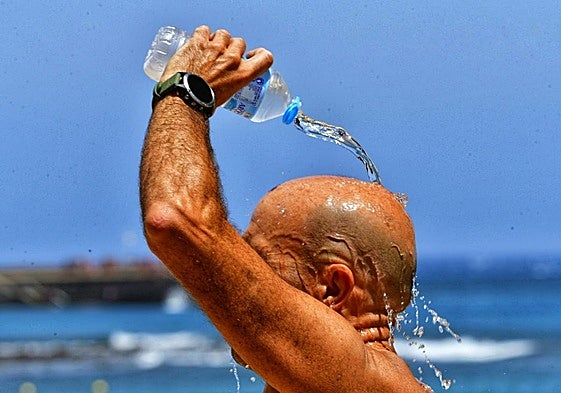 Un hombre se refresca la cabeza con agua para combatir las altas temperaturas.