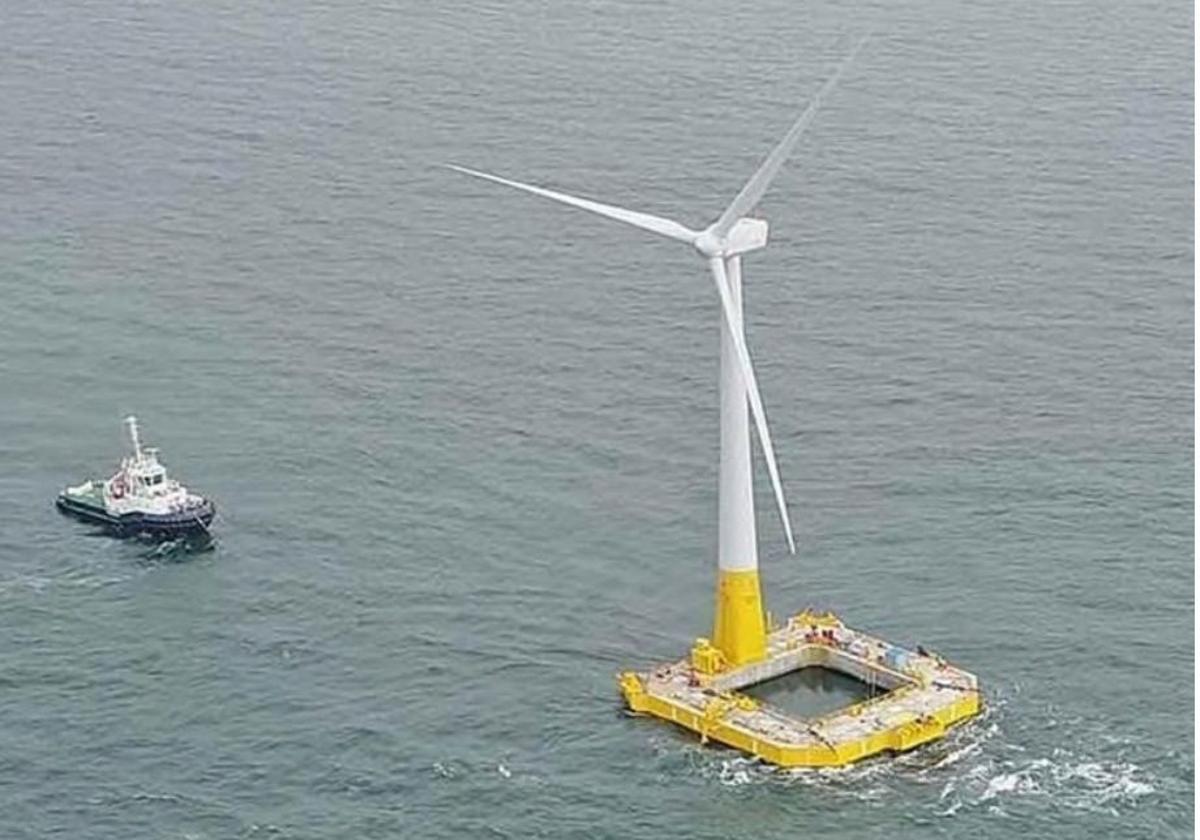 Un remolcador transportando un aerogenerador marino flotante a su ubicación en el mar.